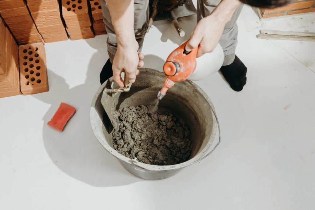 A construction man wets a cement solution in a bucket.