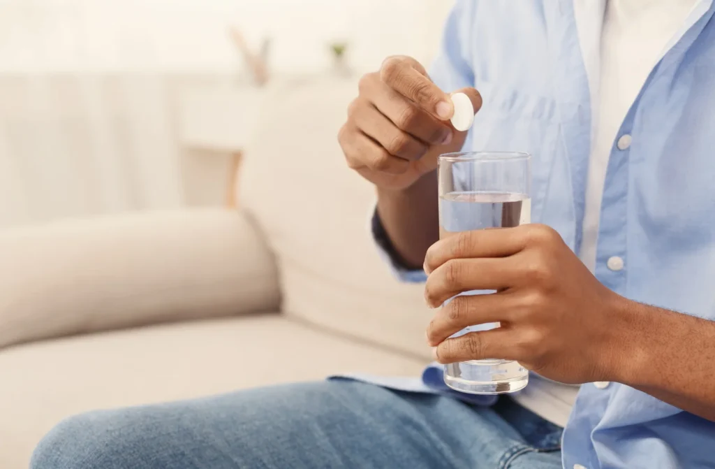 homem-segurando-um-pilula-branca-soluvel-e-um-copo-de-agua